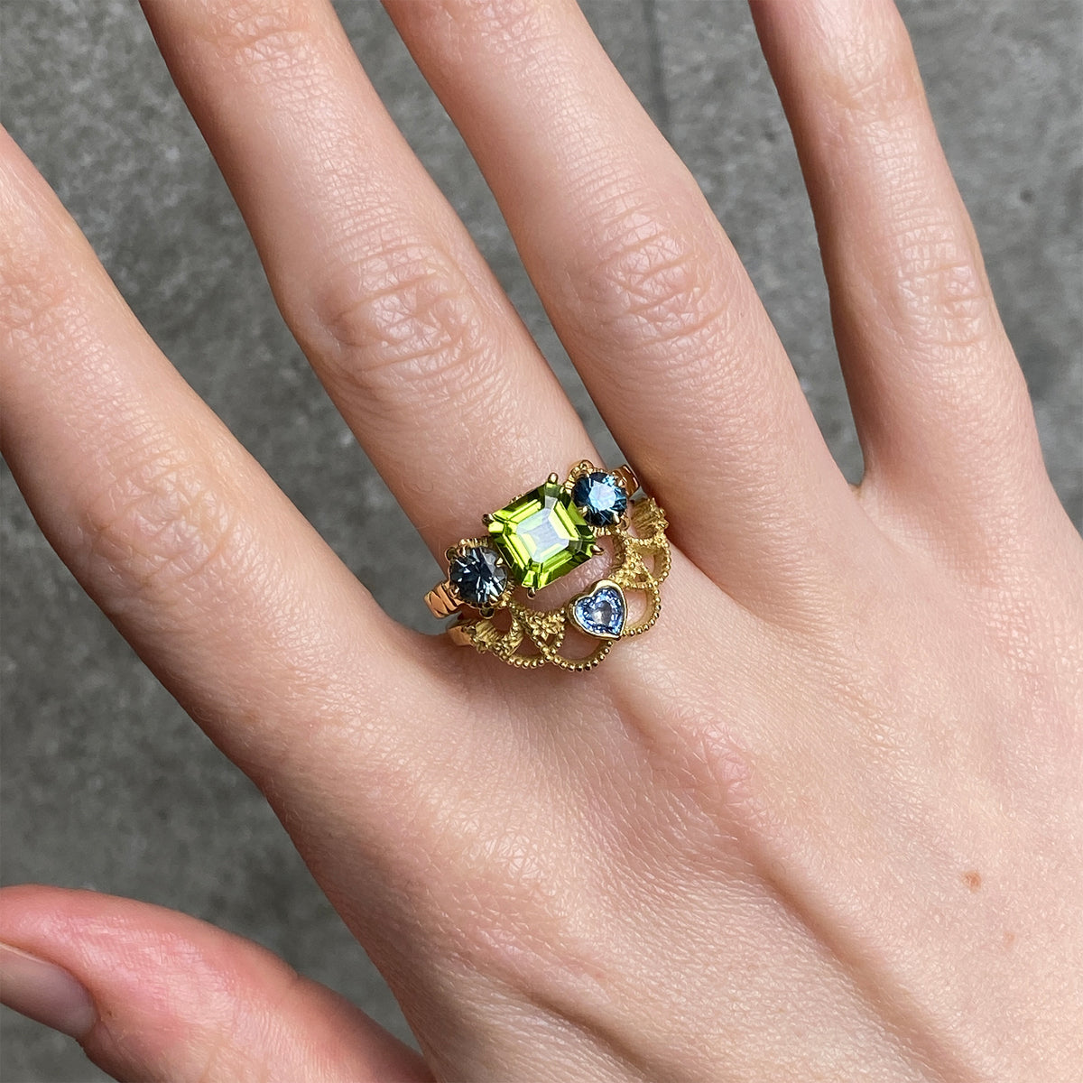 Two rings worn together. One with a green peridot and blue sapphires and the other with a heat shaped blue stone.