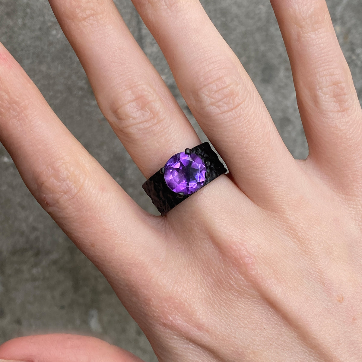 round purple ring on a black band worn on a hand
