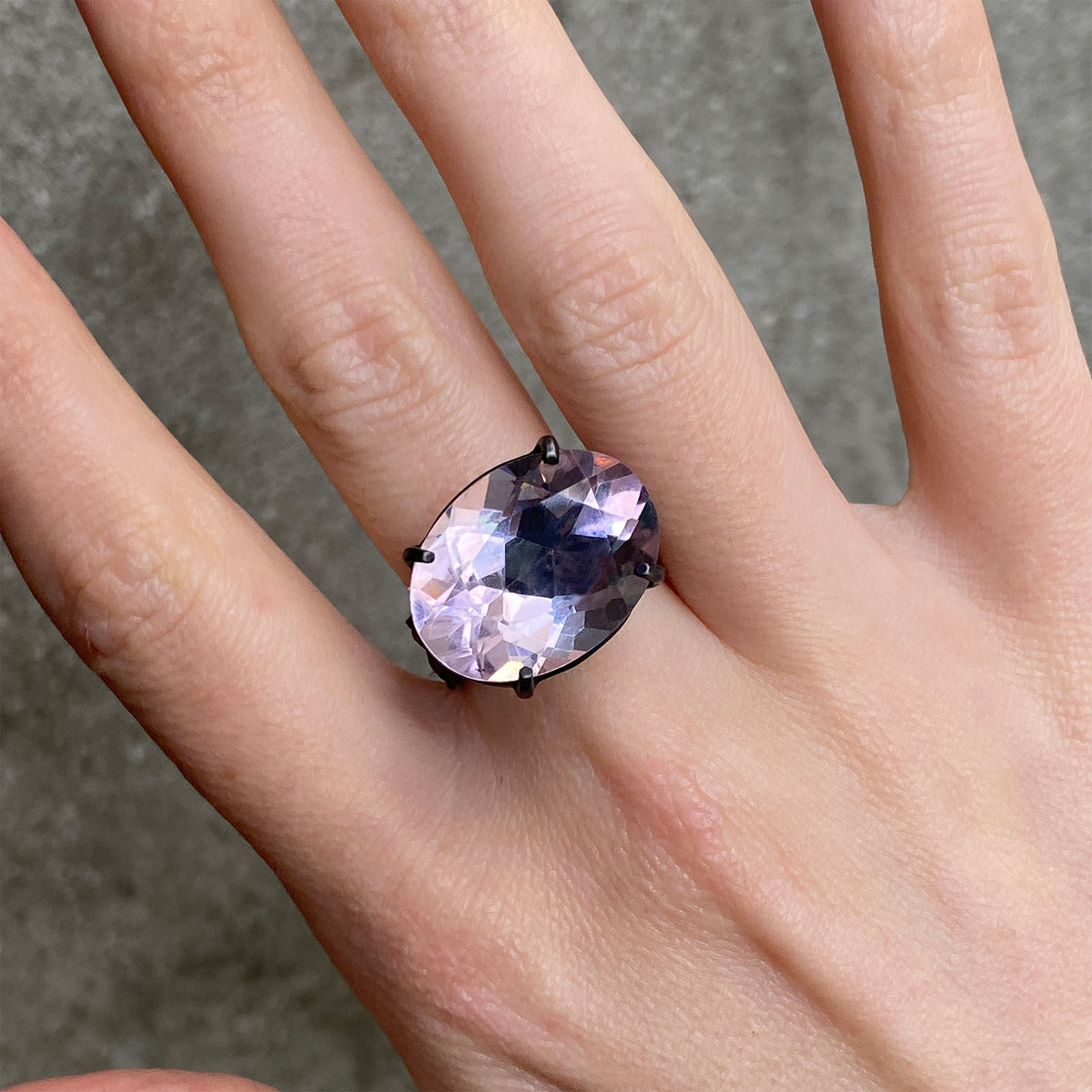 Large oval amethyst stone on a black band worn on a hand