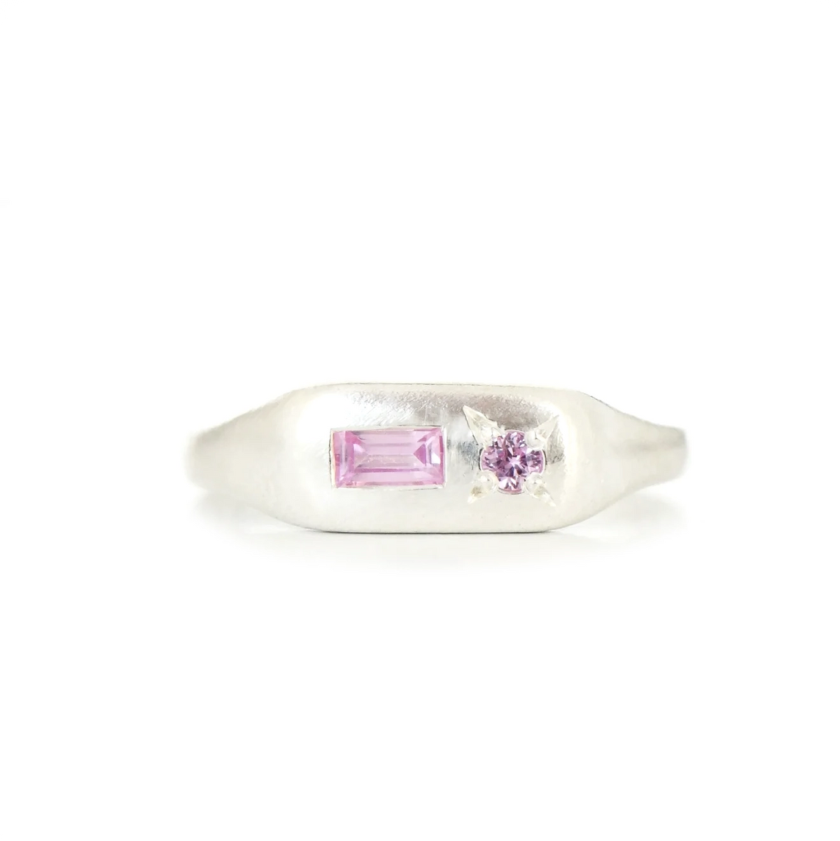 A silver signet ring featuring a rectangular pink gemstone and a small round pink gemstone on a plain white background.
