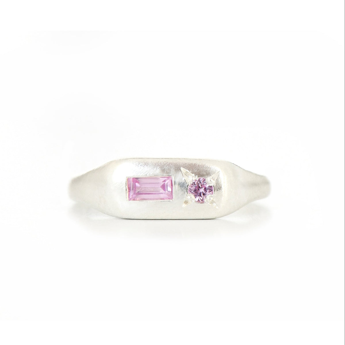 A silver ring featuring a rectangular pink gemstone and a small round pink stones on a white background.
